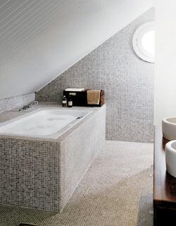Ruskea värimaailma: Kylpytilan seiniä ja lattiaa verhoilee Cloudy Grey -marmorimosaiikki, joka taipuu upeasti kylpyammeen muotoihin.