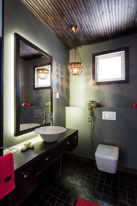 Huolimatta tummasta värimaailmasta, wc-tila ei ole synkkä. Tummaksi käsitelty katto toistaa lattian värisävyjä
