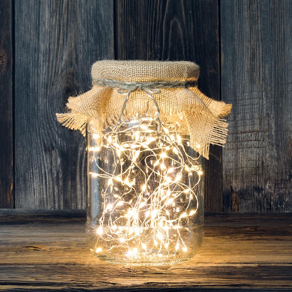 Vanhan lasinpurkkiin saat uutta elämää koristevaloilla. Valojen paristokotelon piilotat helposti juuttikankaan alle kanteen teippaamalla. (Kuva: Shutterstock)